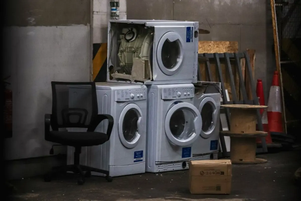 a stack of old washers and dryers in a garage