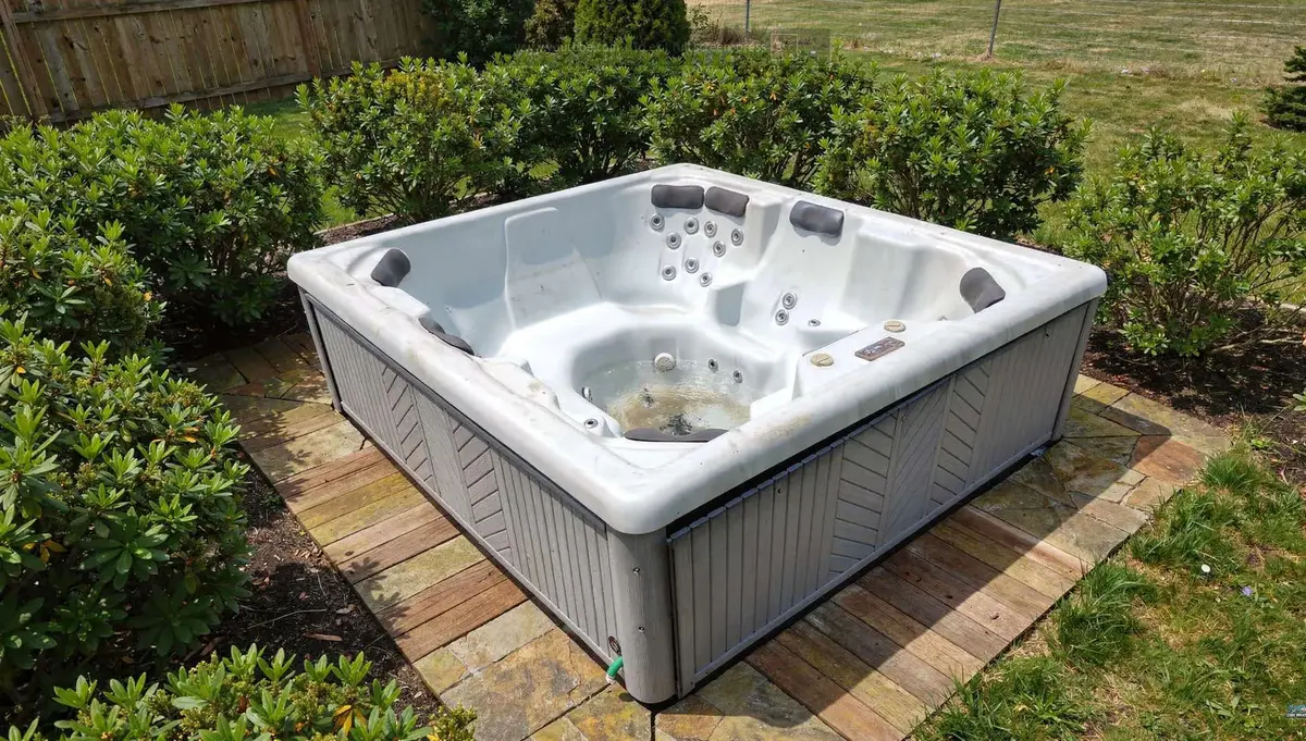 a hot tub on a backyard patio before demolition